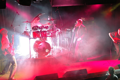 Full band shot of Counterfist lit in red with a white explosion behind them at the Fenix Underground.  John Schlick was the Lighting Designer for this show.